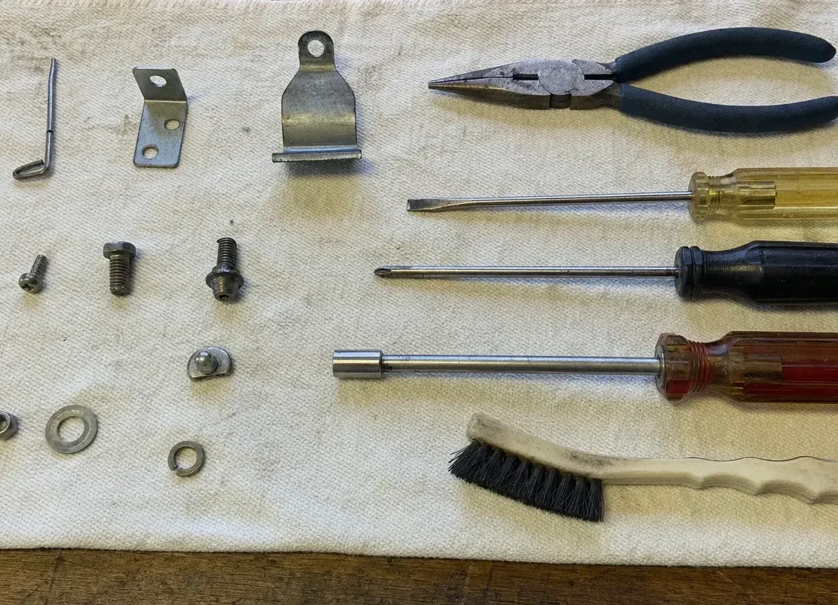 Steel brackets, screws and washers with pliers, screwdrivers and a brush on a work cloth